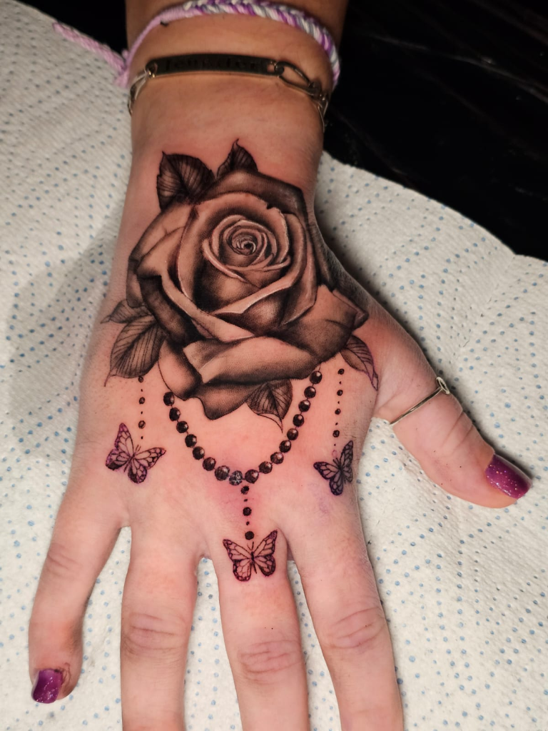 Tatouage rose et papillons sur la main - Monter Tattoo Reims